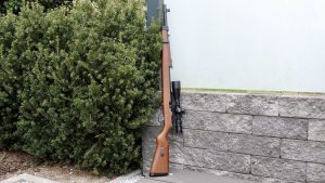 Mauser K98 PCP mit Hawke Airmax 6-24x50 Compact Zielfernrohr an Hecke abgestellt